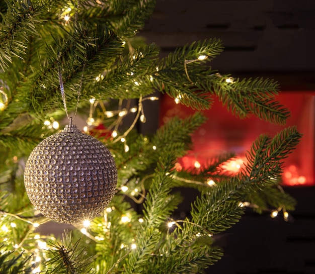 Christmas tree decoration bauble and lights close up burning fireplace background