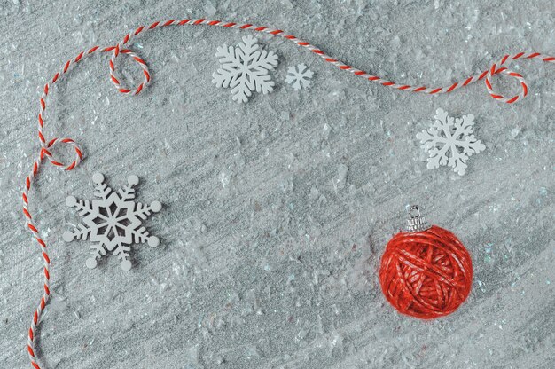 Christmas tree decoration made of red yarn ball and white wooden snowflakes on silver background