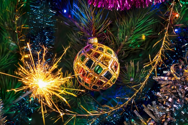 Christmas tree decoration with a shiny ball and sparkler fireworks with fiery sparks