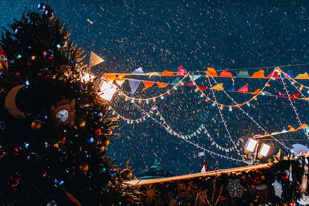 Christmas tree and flying snow in the evening light in festive magic New Year atmosphere