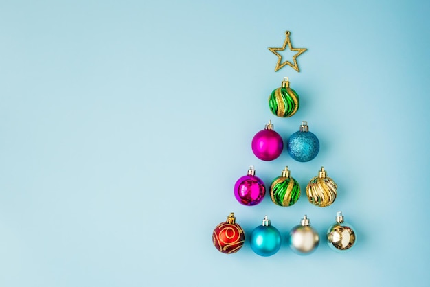 Christmas tree from baubles and golden star on blue pastel background