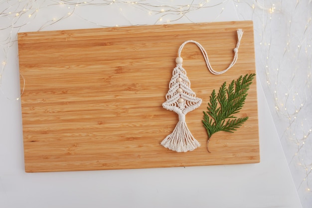 Christmas tree macrame toys on wooden boad White background Natural materials cotton thread wood beads and stick Eco decorations ornaments hand made decor Winter and New Year holidays