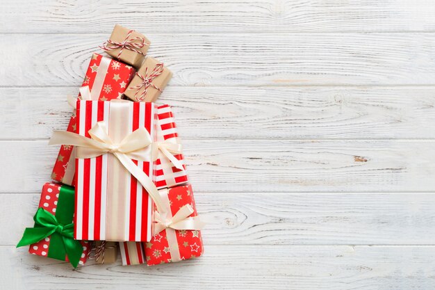 Christmas tree made of beautifuly wrapped presents on colored background, view from above. New Year gift box minimal concept with copy space