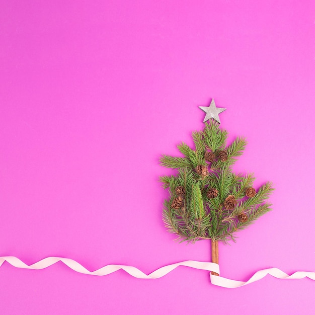 Christmas tree made from fir branches, pine cones and a cinnamon stick as the trunk, pink greeting