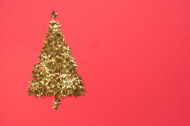 Christmas tree made of golden stars glitter confetti on red background. Xmas holiday .