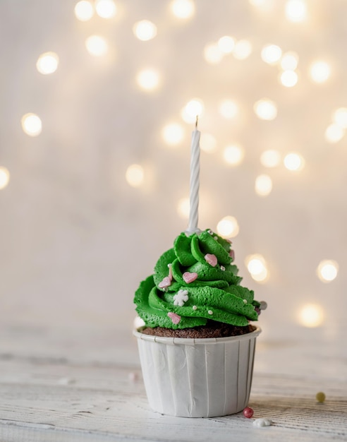 Photo christmas tree shaped cupcakes, surrounded with festive decorations and lights on the background