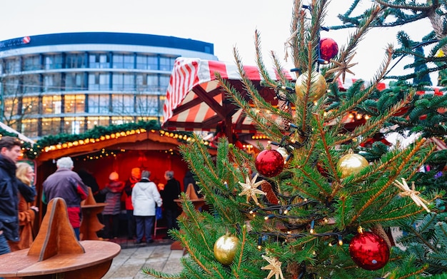 Christmas Tree and stalls in Christmas Market at Kaiser Wilhelm Memorial Church in Winter Berlin, in Germany. Advent Fair Decoration and Stalls with Crafts Items. Glass