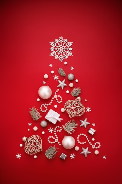 Christmas tree symbol made of white New Year decorations on red background.