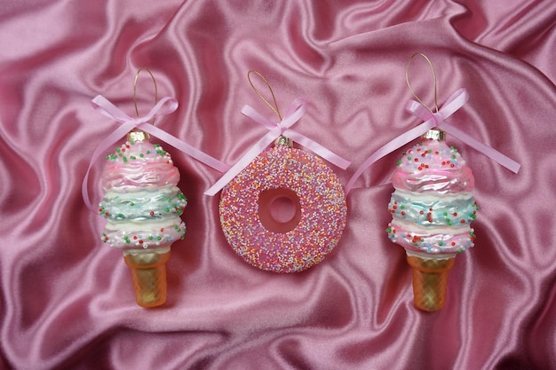 Christmas tree toys in the form of sweets lie on a pink silk background