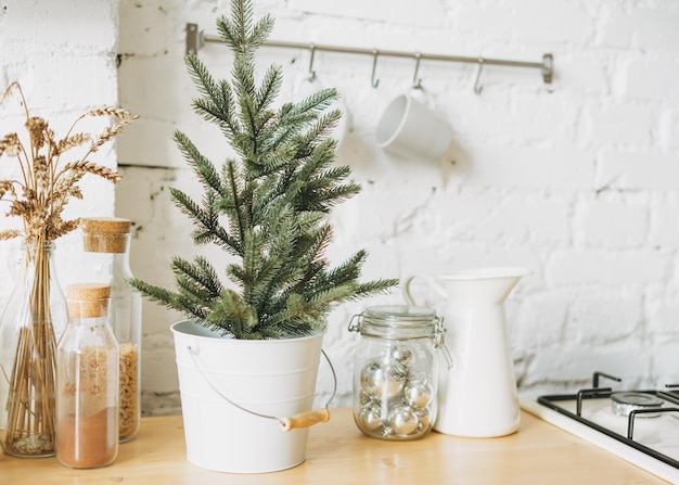 Christmas tree in white pot on the bright kitchen cozy home