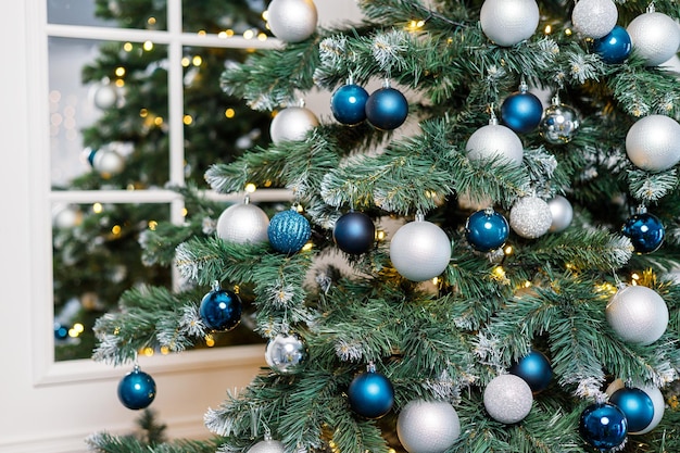 Christmas tree with blue and silver toys Festively decorated Christmas tree with garlands Symbol of the new year