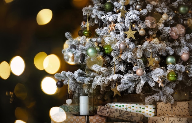 Christmas tree with different decoration and many gifts on blurred background with bright lights