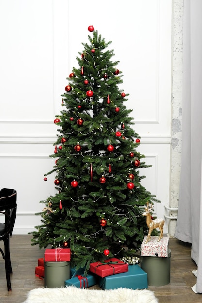 Christmas tree with gifts stands in the classic interior of the living room