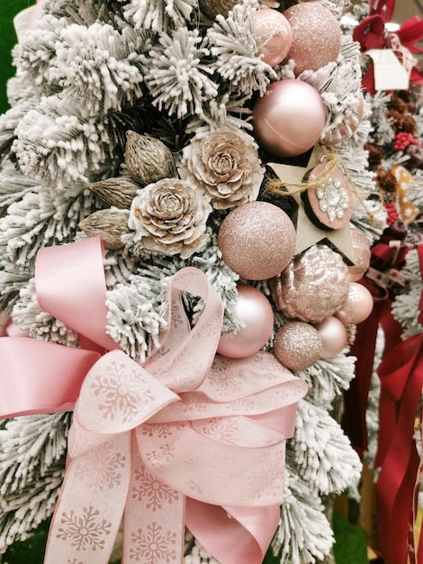 Christmas tree with pink bows all covered with snow and pine cones