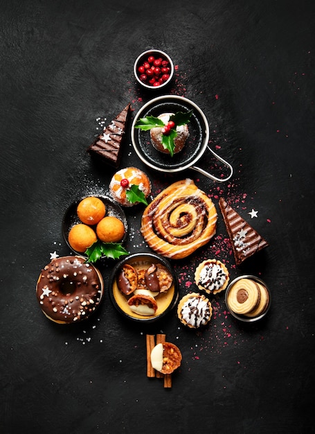 Christmas tree with sweets and cookies decoration on dark background Holiday food Top view copy space