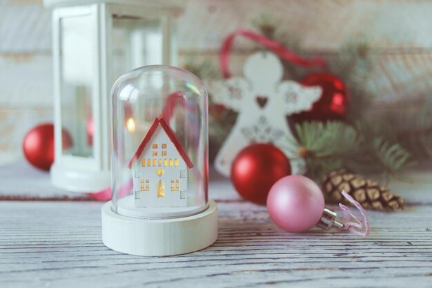 Christmas, white lantern with a burning candle, toy angels, on a wooden background