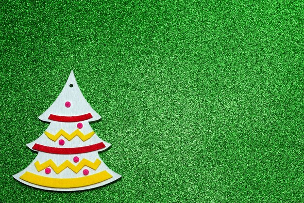 Christmas white wooden handmade toy in the shape of a Christmas tree on a glittering background