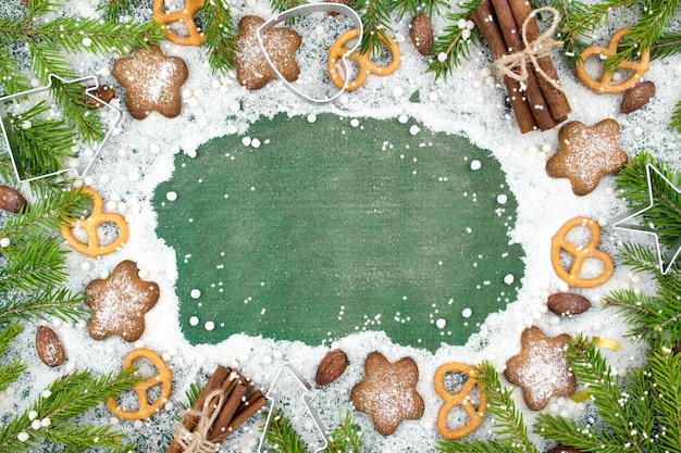 Christmas winter background Spicy ginger cookies pretzels flour Copy space Slate and snow Fir twigs