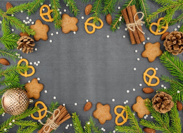 Christmas winter background Spicy ginger cookies pretzels flour Copy space Slate and snow Fir twigs