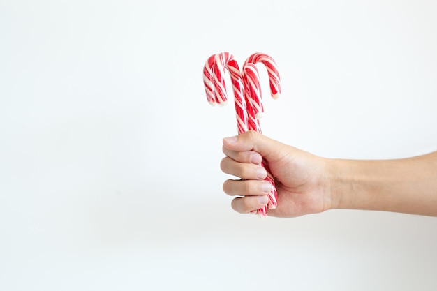 Christmas, winter concept. Holidays, sweets, treats. Man hands holding traditional striped candy cane in shape of bouquet. Male hand holds Christmas candy cane