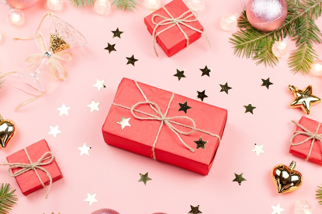 Christmas with fir tree branches, red giftboxes,  golden decorations on pink.