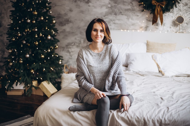 Christmas woman near a Christmas tree on bed at home