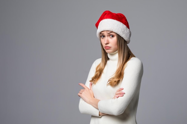 Christmas woman offended in Santa hat isolated on a gray wall