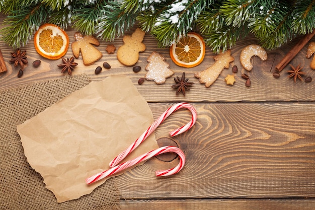 Christmas wooden background with snow fir tree spices gingerbread cookies