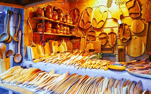 Christmas Wooden Kitchen Utensils Decorations on Christmas Market at Riga, Latvia. Advent Fair, and Stalls with Crafts Items in Bazaar. Night street Xmas and holiday fair in European town, December.