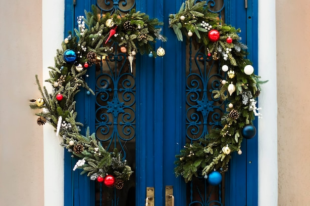 Christmas wreath from a Christmas tree on a blue door of the house with Christmas toys ribbons