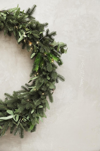 Christmas wreath made of fir branches hanging on a gray wall Half wreath