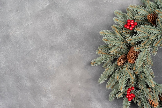 Christmas wreath made of natural fir branches hanging on a gray wall New year and winter holidays