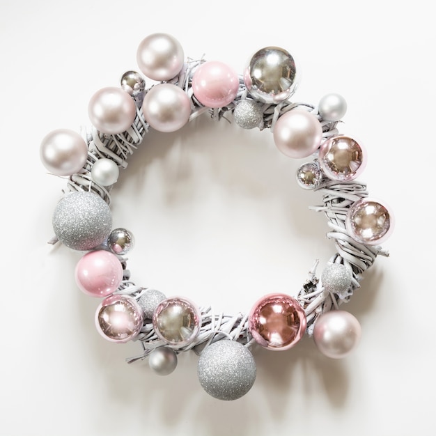 Christmas wreath with silver and pink balls on white.