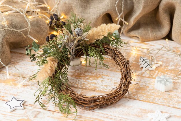 Photo christmas wreath on wooden background with floral decor and lights