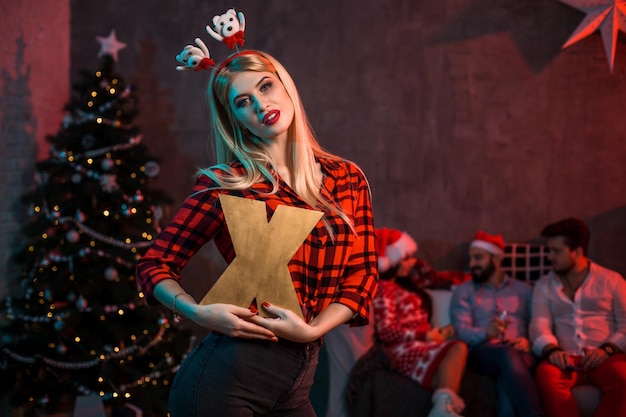 Christmas, x-mas, New year, winter, happiness concept - smiling woman in santa helper hat with a wooden letter X.