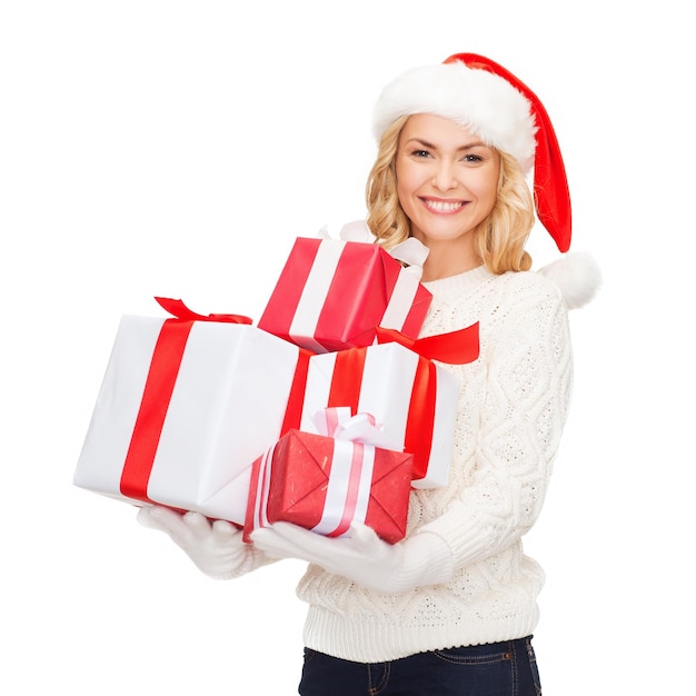 christmas, x-mas, winter, happiness concept - smiling woman in santa helper hat with many gift boxes