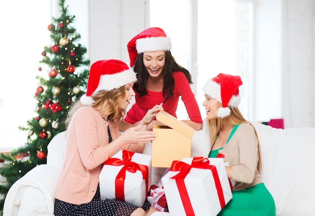 christmas, x-mas, winter, happiness concept - three smiling women in santa helper hats with many gift boxes