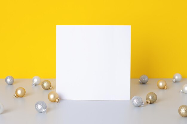 Photo christmas yellow and grey minimal background with mock up greetings card and ball close up copy space