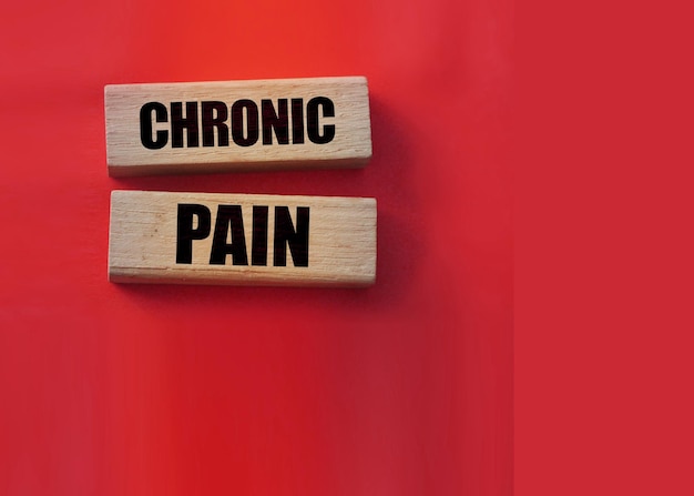 Chronic pain words on wooden blocks on red background Medicine concept