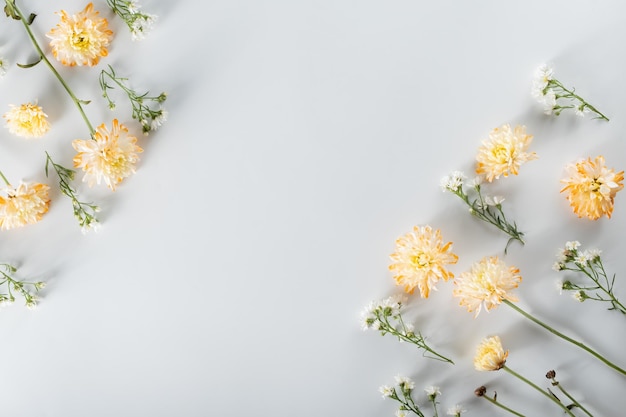 Chrysanthemum and cutter flowers composition Pattern and Frame made of various yellow or orange flowers and green leaves on white background Flat lay top view copy space spring summer concept