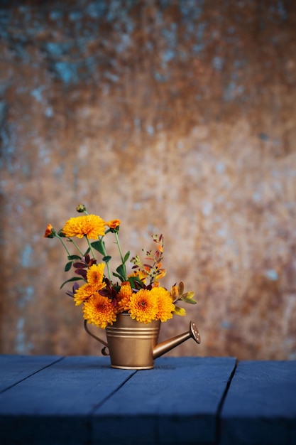 Chrysanthemum flowers in jug on background old wall in sunlight