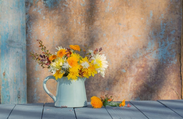 chrysanthemum flowers in jug on background old wall in sunlight