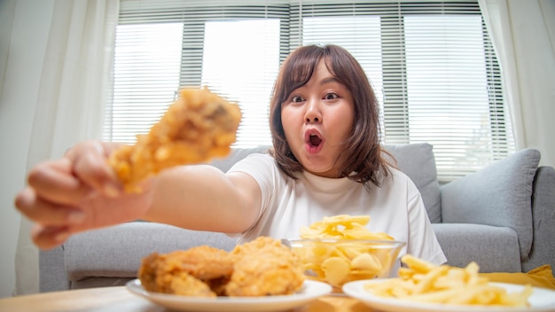 Chubby Asian woman express happiness When eating fried chicken fries and potato snacks