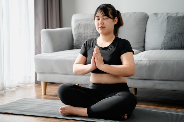 chubby woman sitting on the floor in living room practice yoga lesson female having meditate class