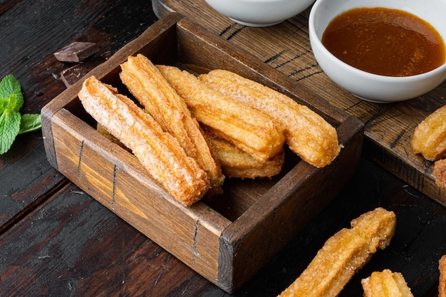 Churros sprinkled with powdered sugar set, on old dark  wooden table background