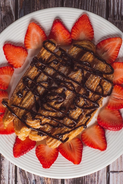 Churros with chocolate and strawberries on a white plate.