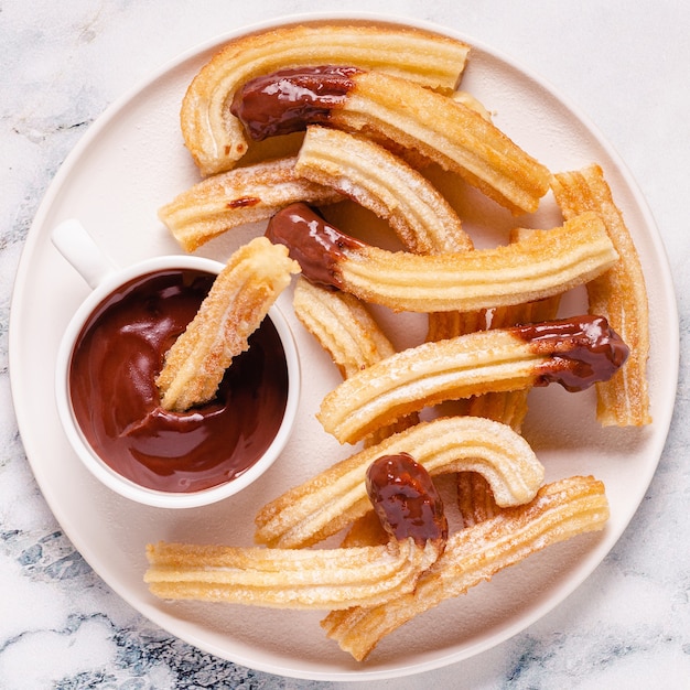 Churros with powdered sugar and chocolate sauce, top view.