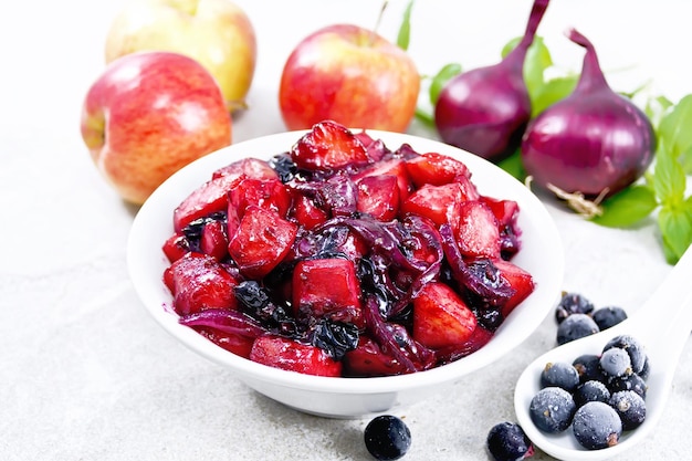 Chutney of apple and blackcurrant in bowl on gray stone