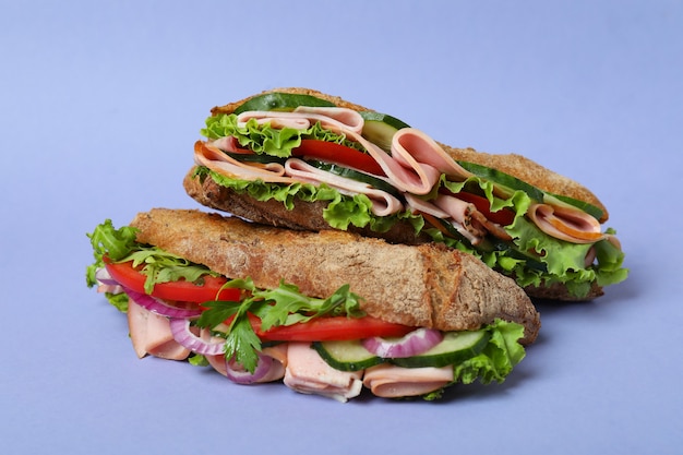 Ciabatta sandwiches on violet background, close up