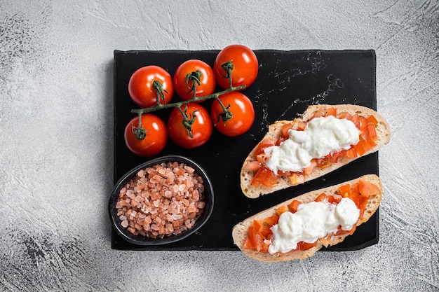 Ciabatta toasts with stracciatella cheese chopped tomatoes and basil White background Top view